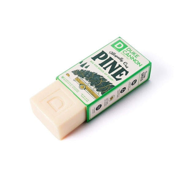 A bar of Duke Cannon soap with packaging that has a green and white color scheme and text that reads 'Illegally Cut Pine' and '10 oz.'.