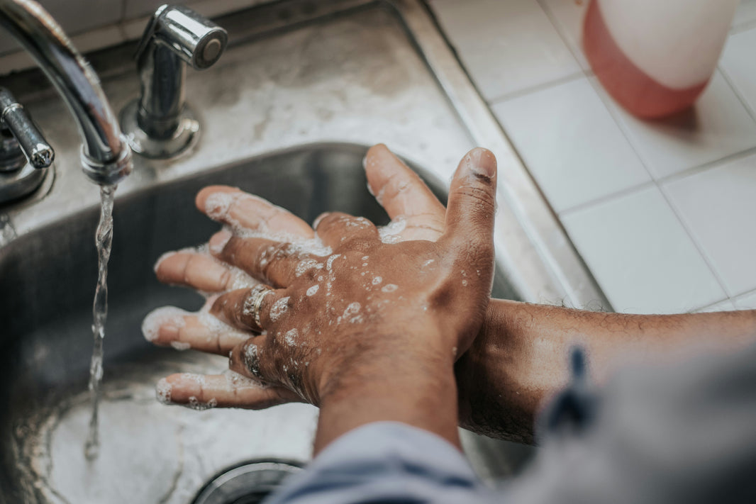 Person washing hands under running water in a sink.