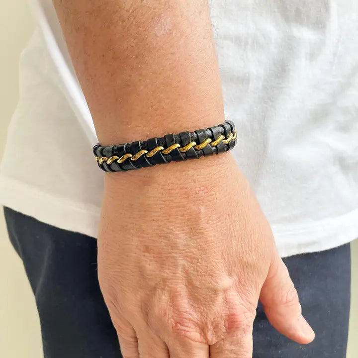 Black and gold braided bracelet on a wrist with a white background