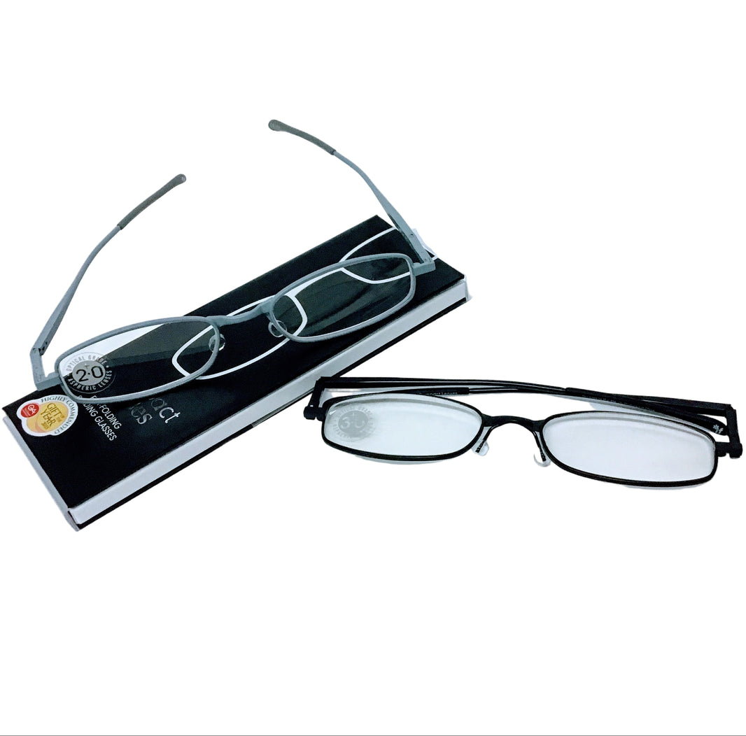 A pair of compact folding reading glasses with a metallic frame, displayed next to its packaging.