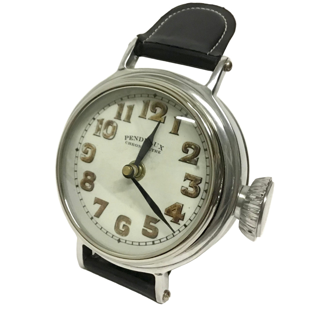 A silver wristwatch-style table clock with a white face, black leather straps, fashioned to sit on a desk, on a white background.