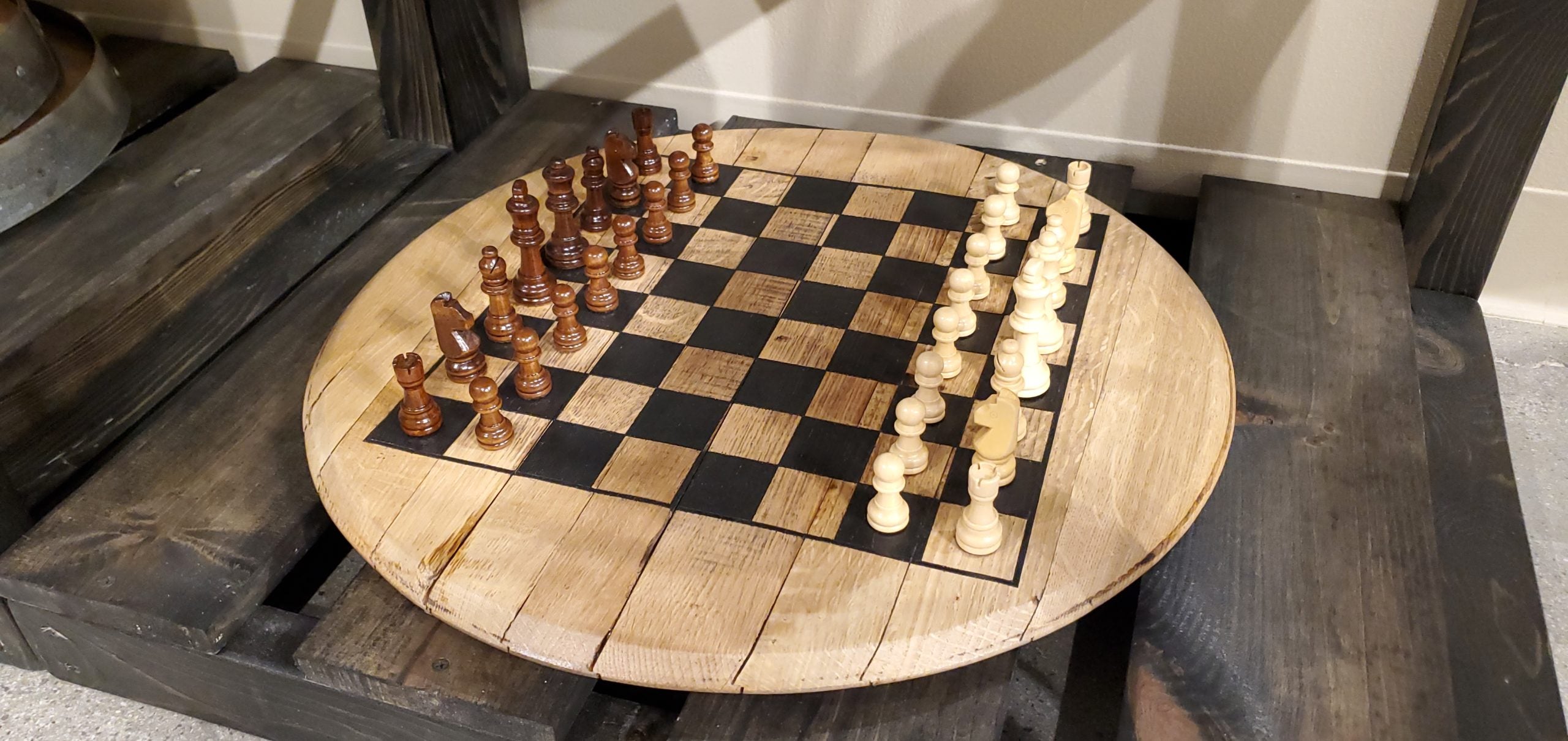 Wooden chessboard with black and white chess pieces on a wooden table