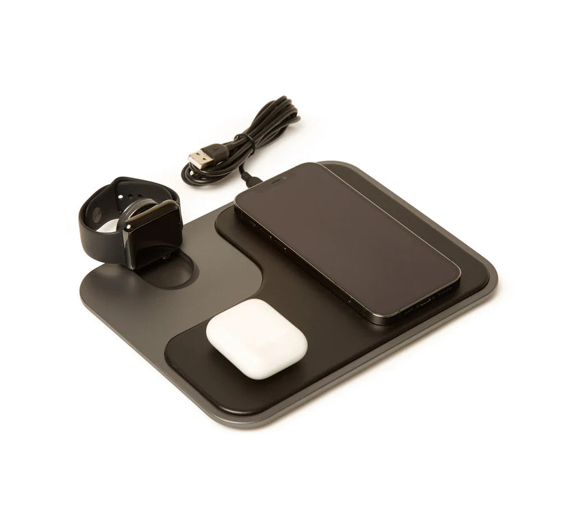 Black and gray wireless charger with a watch, phone, and earbud case on it, on a white background