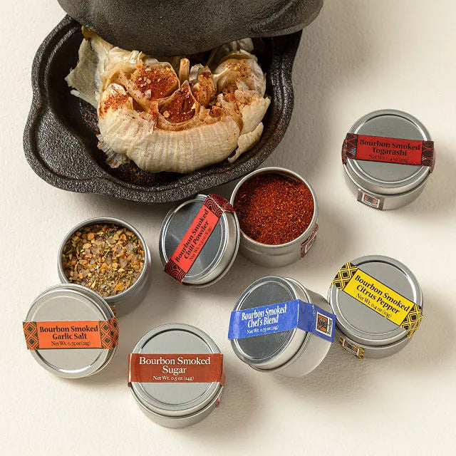 Assorted bourbon smoked spices in small metal containers on a light background