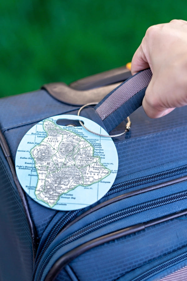 A circular luggage tag with a map on it, attached to a piece of luggage.