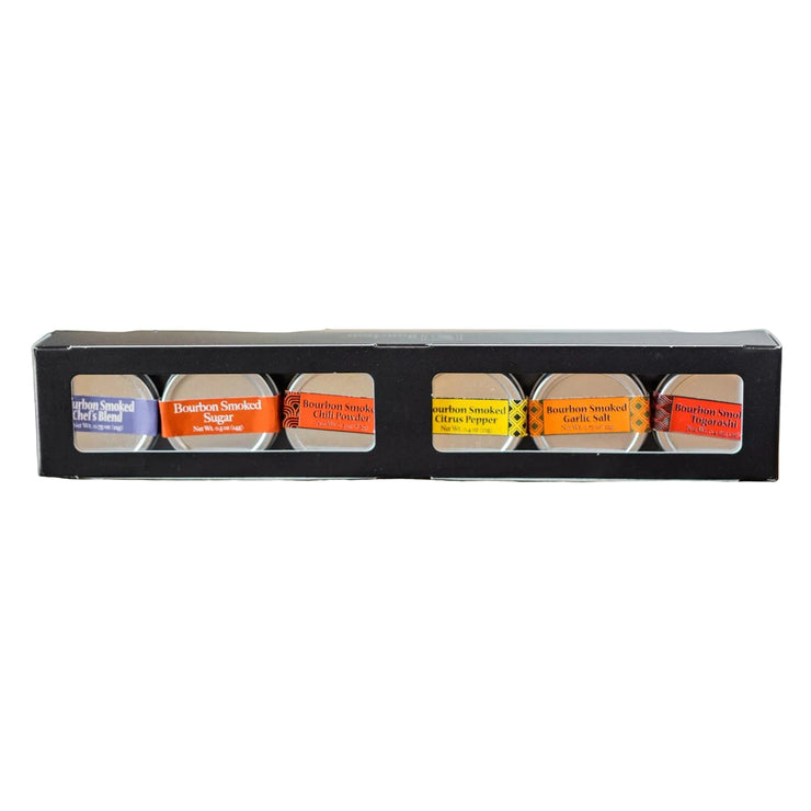Assorted bourbon smoked spices in small metal tins inside of a black container on a light background
