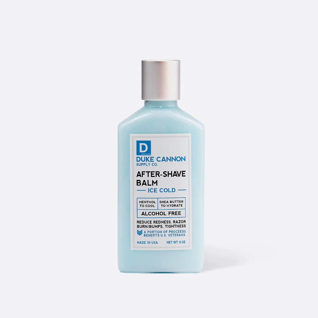 A bottle of Duke Cannon Cooling After-Shave Balm with menthol, aloe, shea butter, and allantoin, in a light blue color, with text indicating it is alcohol-free.