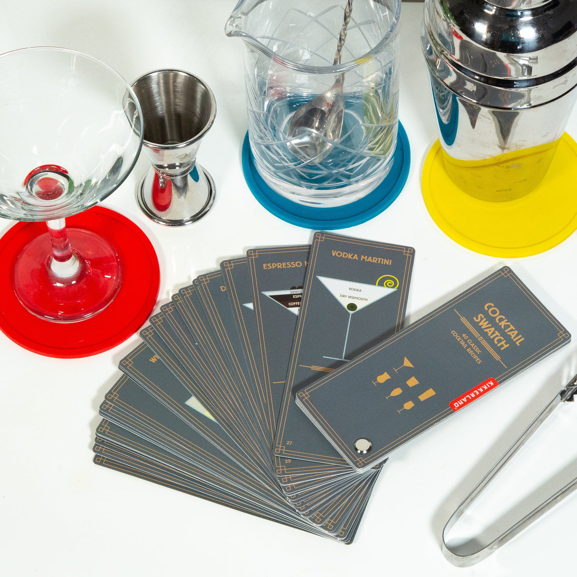 Cocktail swatch cards on a table with barware accessories