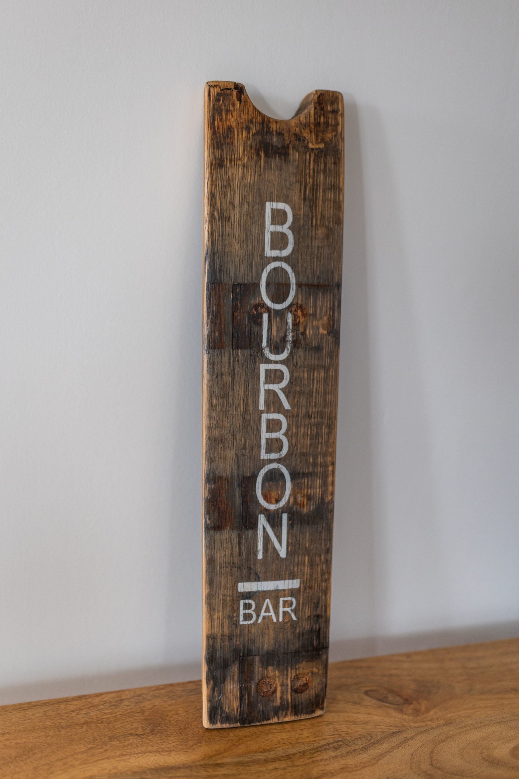 Wooden sign with 'Bourbon Bar' text on a plain background