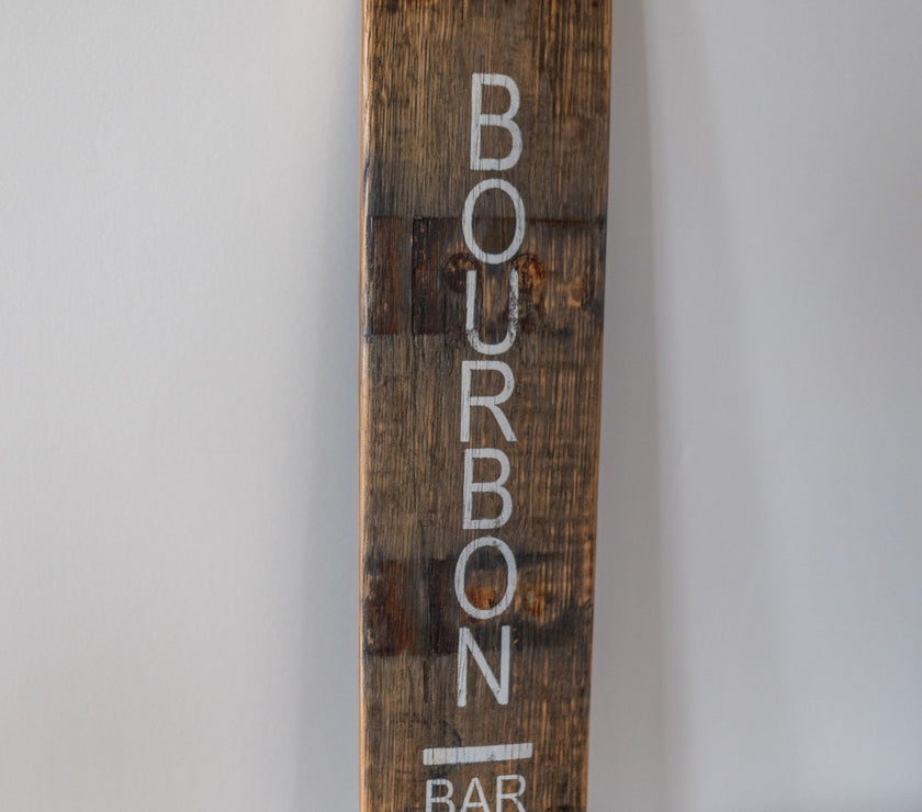 Wooden sign with 'Bourbon Bar' text on a plain background