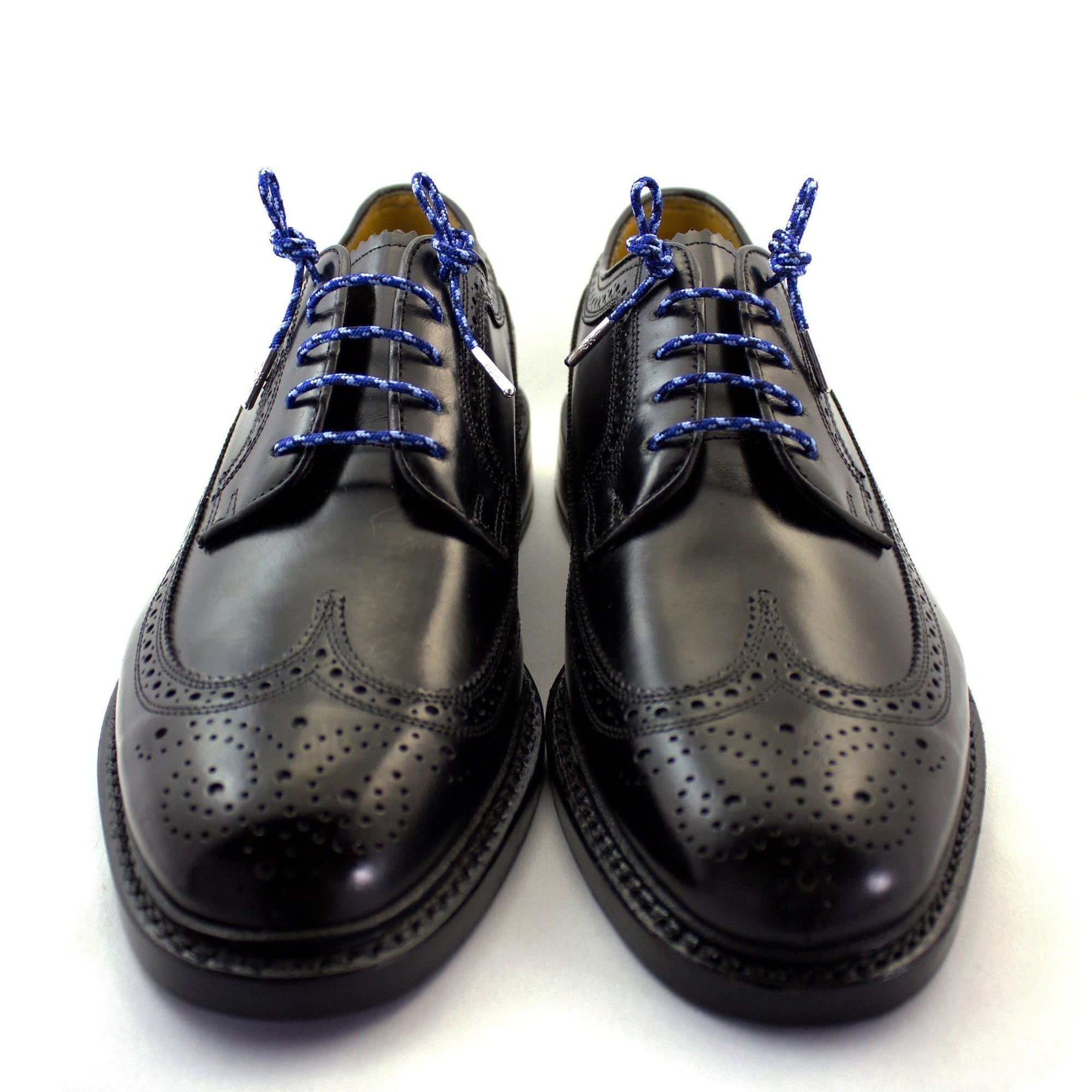 A pair of camouflage blue dress shoelaces with silver tips laced up into a pair of black shoes.