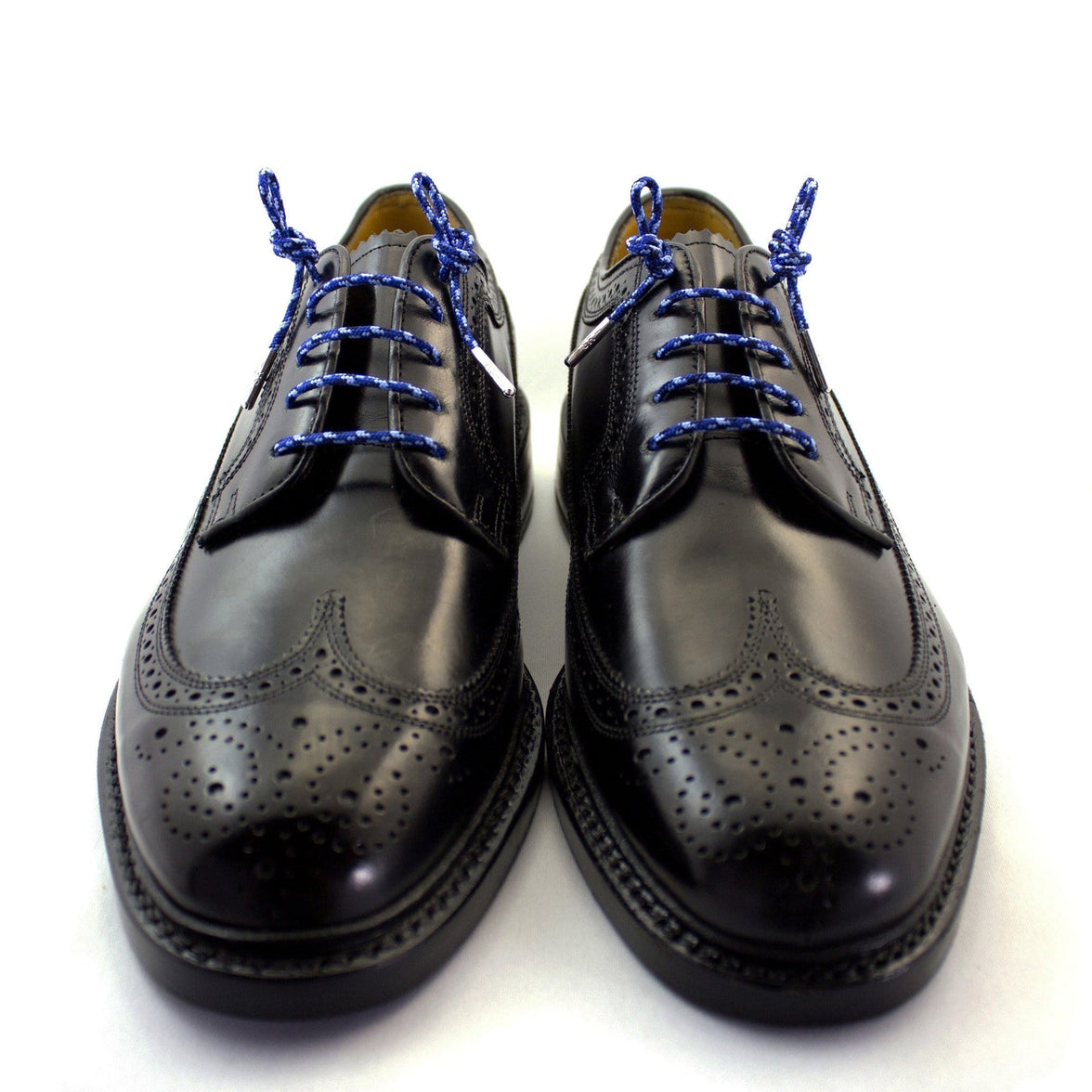 A pair of camouflage blue dress shoelaces with silver tips laced up into a pair of black shoes.