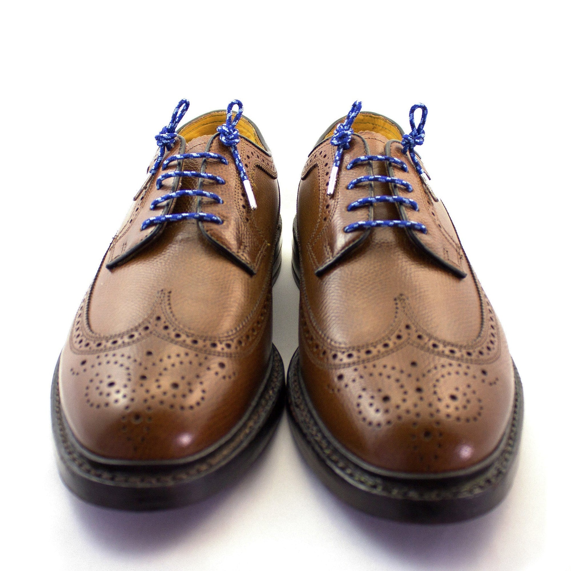 A pair of camouflage blue dress shoelaces with silver tips laced up into a pair of brown shoes.
