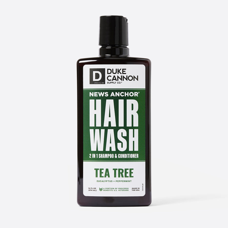 A bottle of Duke Cannon News Anchor Hair Wash 2-in-1 Shampoo & Conditioner with Tea Tree scent, black with green label, 14oz size.