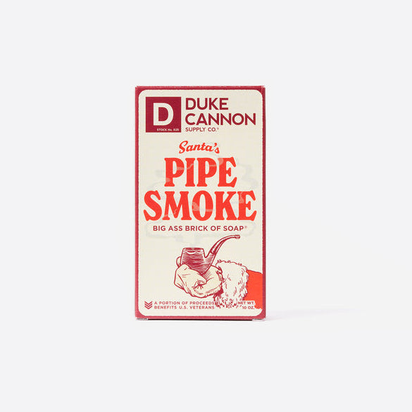A package of Duke Cannon Big Ass Brick of Soap with 'Santa's Pipe Smoke' scent, featuring an illustration of a pipe and Santa Claus.