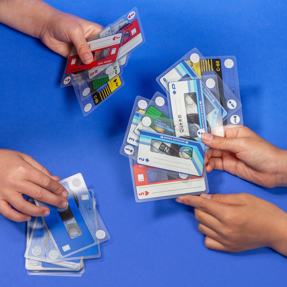 Hands playing with cassette tape-themed cards on a blue background