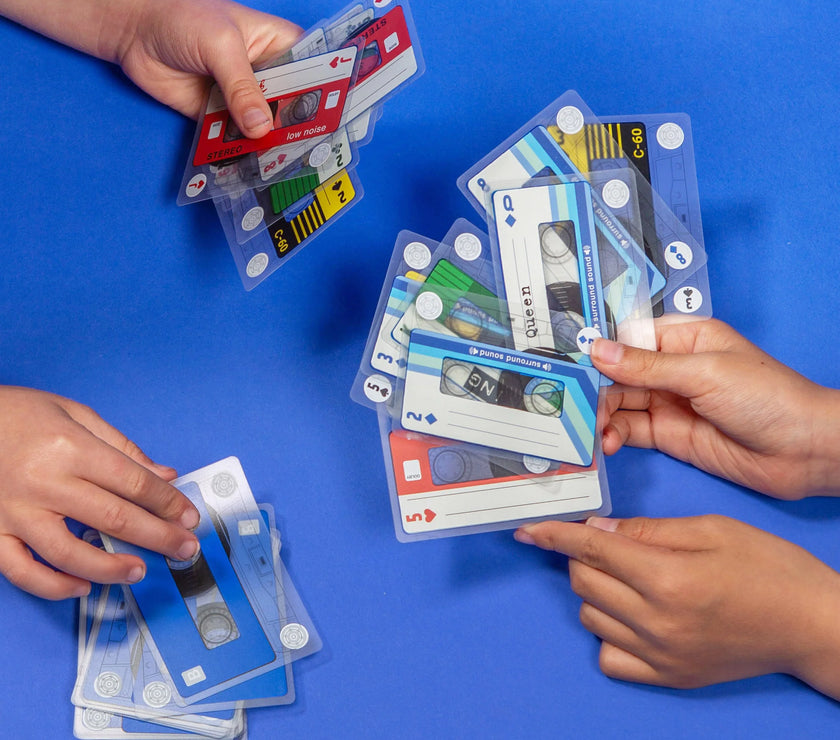 Hands playing with cassette tape-themed cards on a blue background