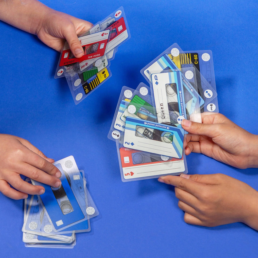 Hands playing with cassette tape-themed cards on a blue background