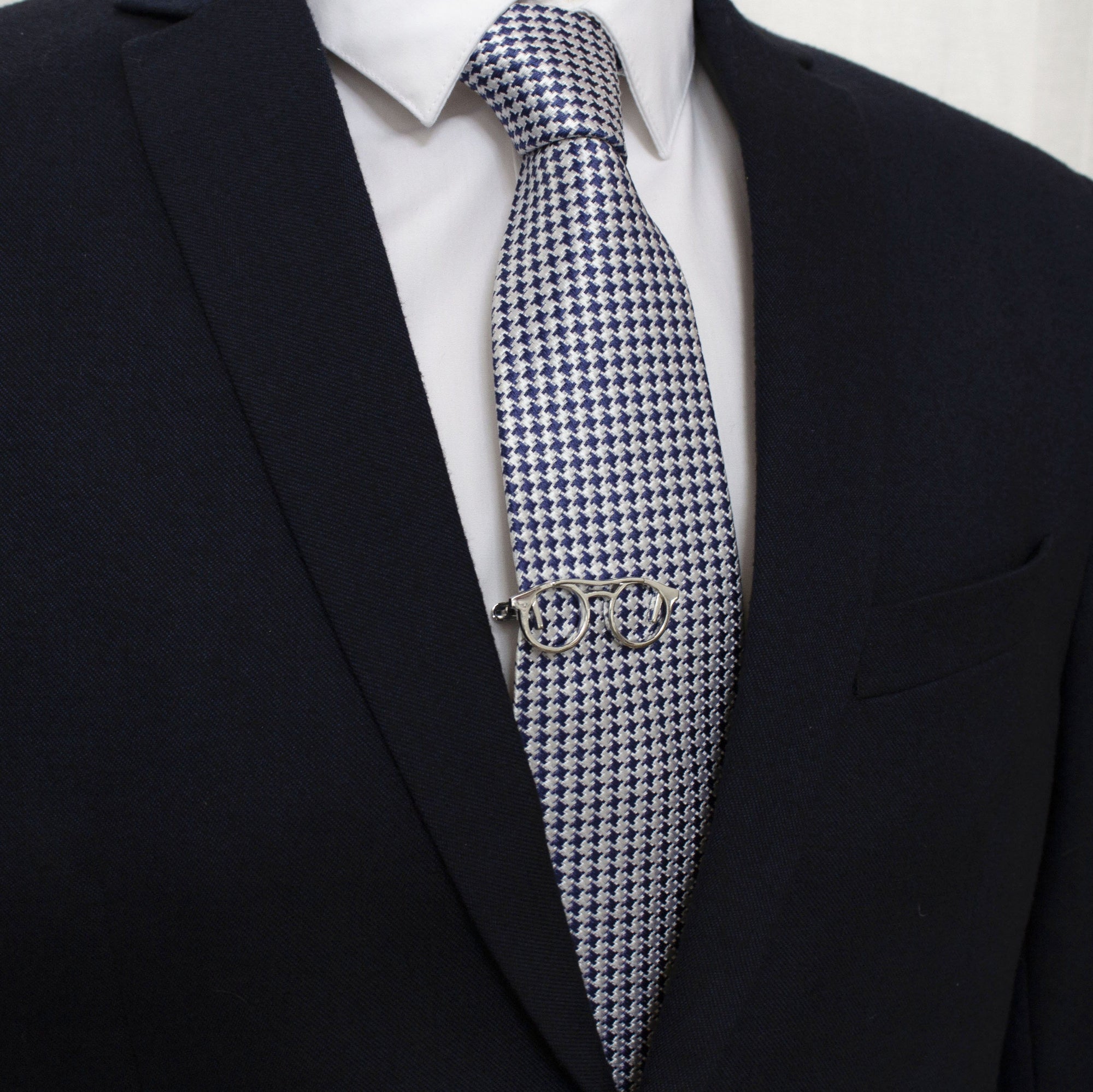 A tie bar shaped like a pair of glasses clipped to a tie.