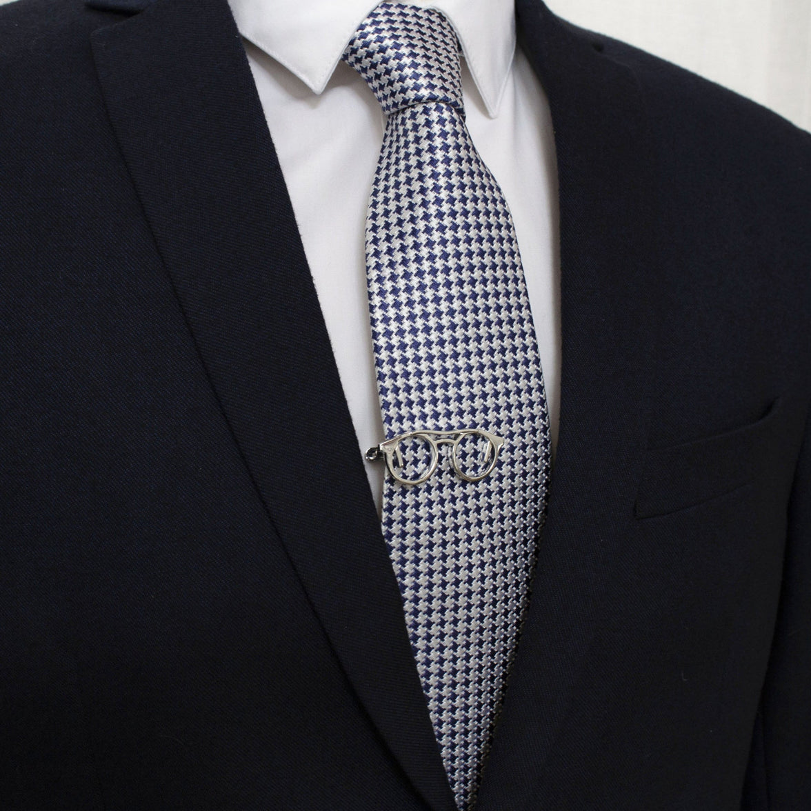 A tie bar shaped like a pair of glasses clipped to a tie.
