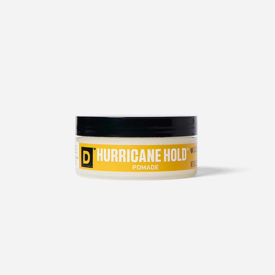 A container of Duke Cannon Hurricane Hold Pomade with a yellow label and black lid on a white background.