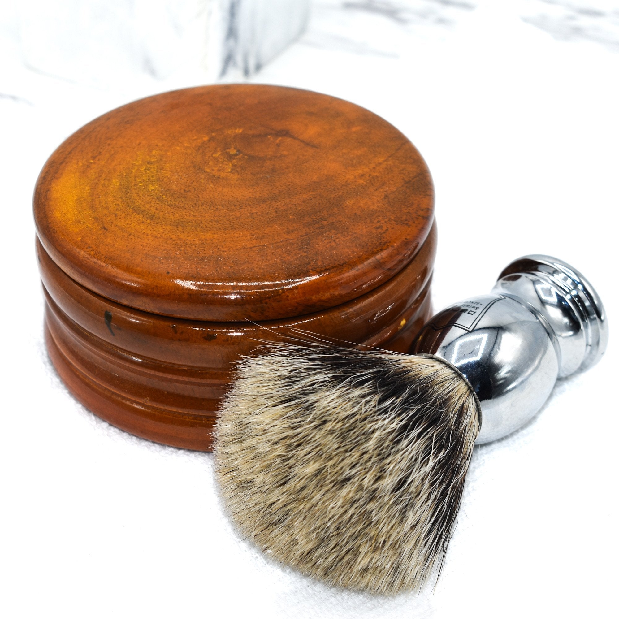 A honey mango wood shaving bowl next to a shaving brush.