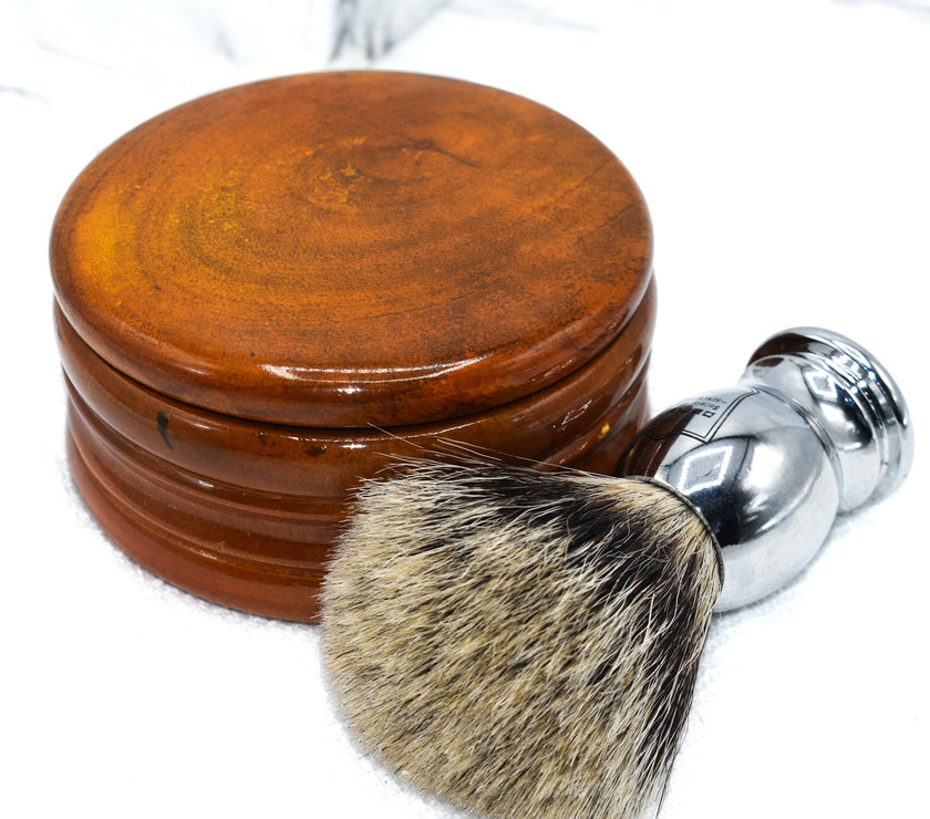 A honey mango wood shaving bowl next to a shaving brush.