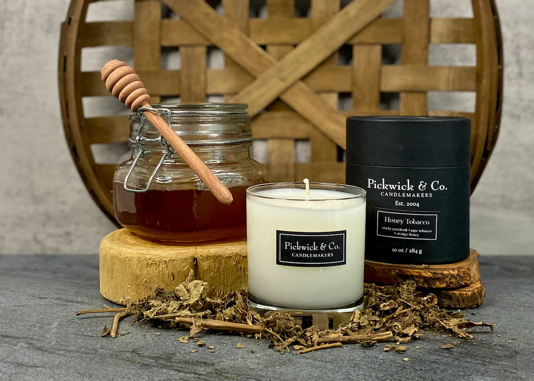 Pickwick & Co candle with jar of honey and honeycomb on a wooden stand.