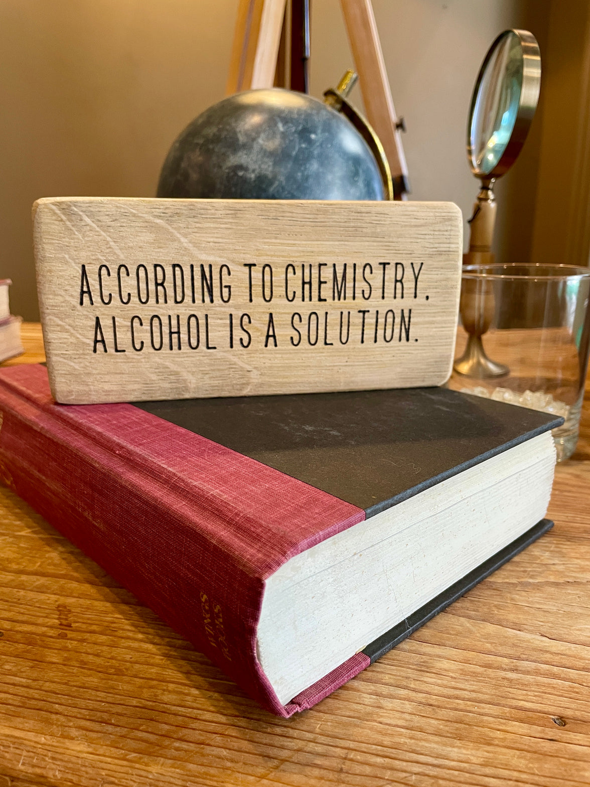Wooden block with text on a book, set against a blurred background of office decor.