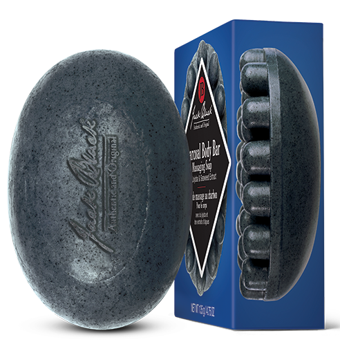 A gray Jack Black Charcoal Body Bar with massaging nubs, displayed next to its blue packaging box.