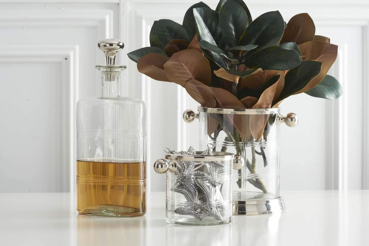 Decorative ice buckets and a decanter with plants on a white surface