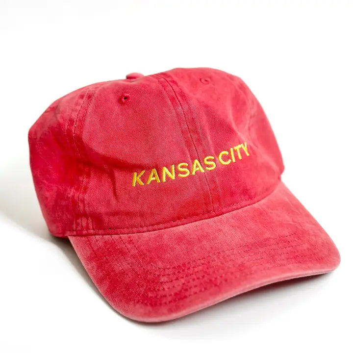 A red embroidered hat with 'KANSAS CITY' text in yellow on the front.