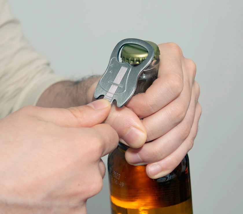 A person using a guitar shaped bottle opener on a bottle of beer.