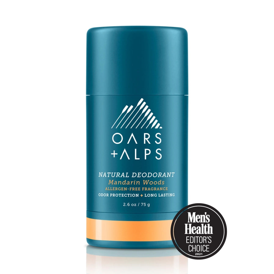 A stick deodorant with blue packaging labeled 'OARS + ALPS NATURAL DEODORANT mandarin woods'. There is a Men's Health Editors Choice badge displayed in front of the product.