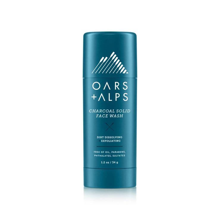 A blue cylindrical container of Oars + Alps Charcoal Solid Exfoliating Face Wash with white and blue label design.