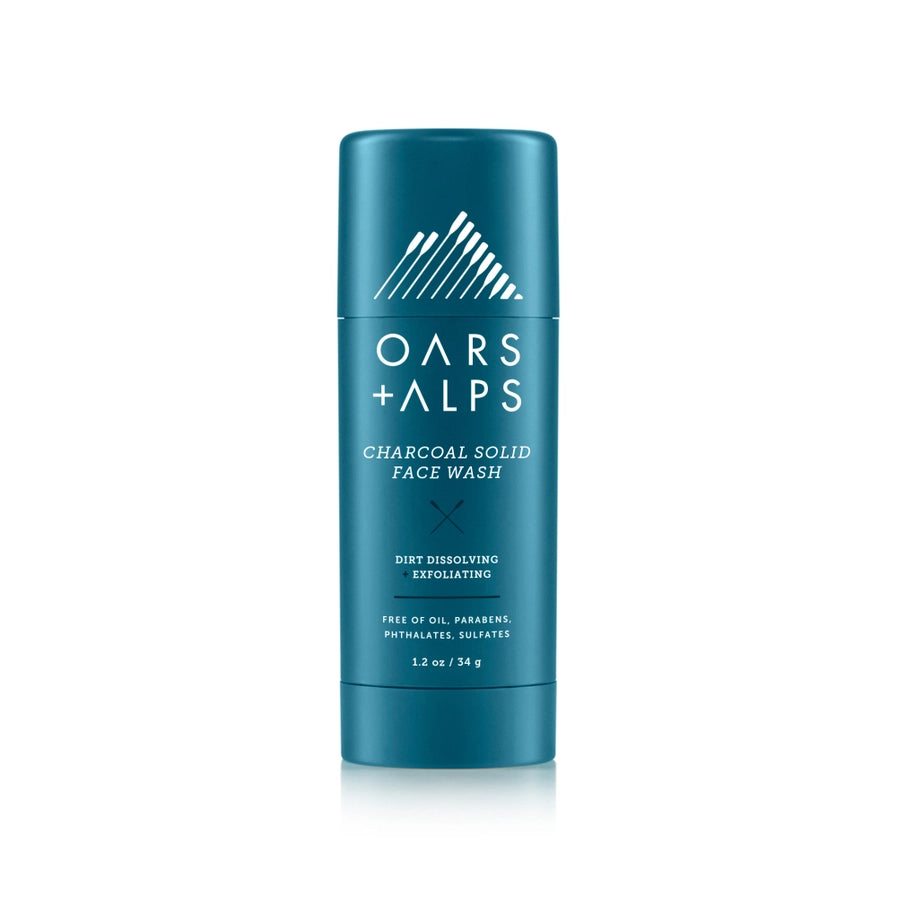 A blue cylindrical container of Oars + Alps Charcoal Solid Exfoliating Face Wash with white and blue label design.