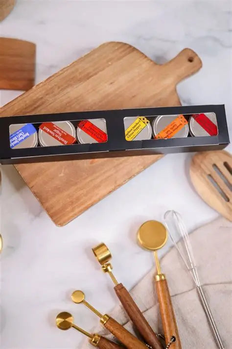 Assorted bourbon smoked spices in small metal containers on a cutting board with other kitchen tools nearby.