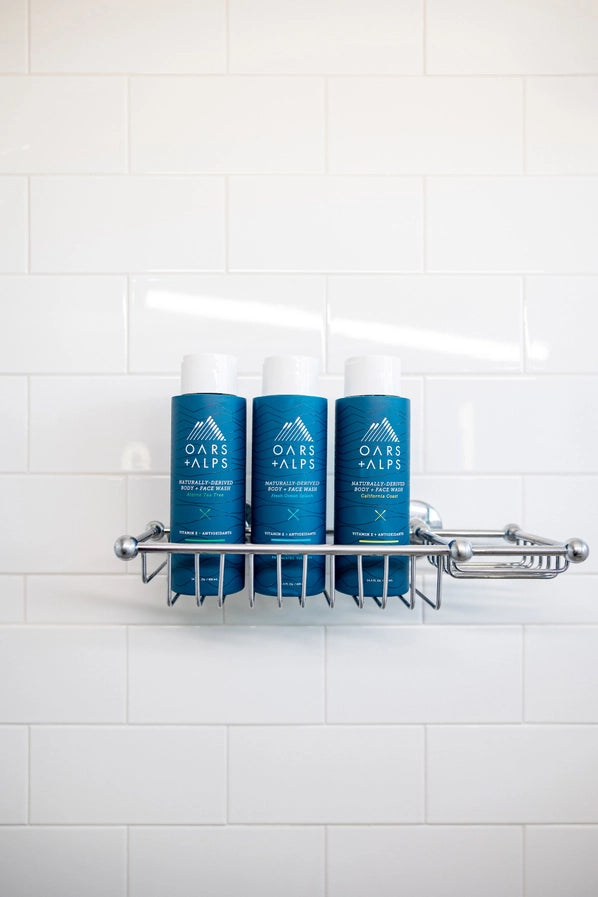 Three bottles of Oars + Alps body wash in a shower tray.