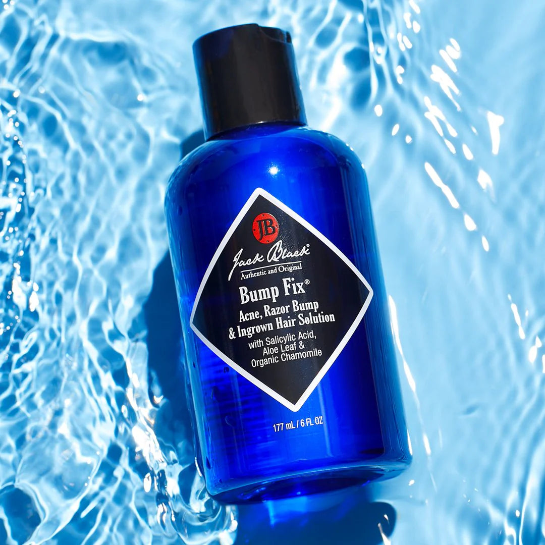 A bottle of Jack Black Bump Fix, a skin care product with a blue label and black cap, designed for reducing bumps and irritation, on a blue watery background.