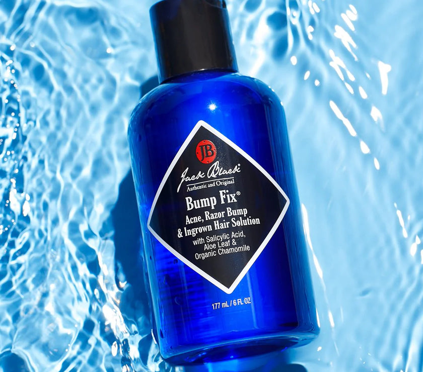 A bottle of Jack Black Bump Fix, a skin care product with a blue label and black cap, designed for reducing bumps and irritation, on a blue watery background.