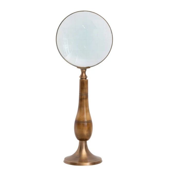 Vintage-style magnifying glass that acts as its own stand on a white background