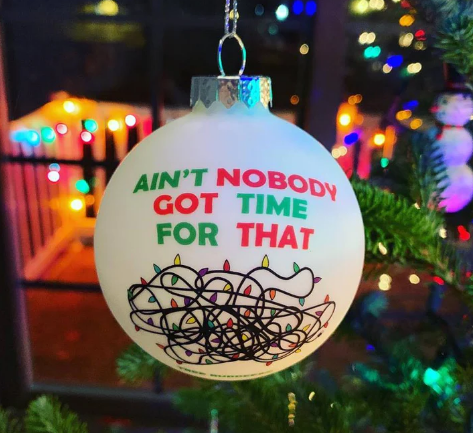 A Christmas ornament with a text message 'Ain't Nobody Got Time for That' surrounded by a tangled light pattern, hanging on a Christmas tree.