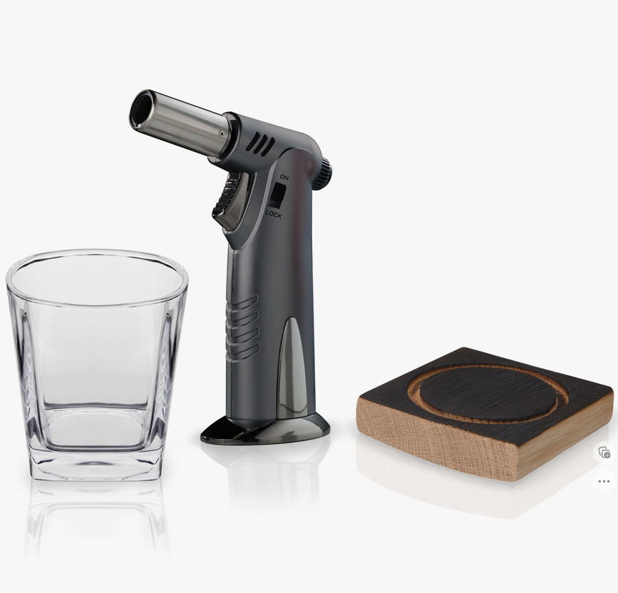 A set consisting of a clear lowball glass, a butane torch, and an American oak whiskey barrel plank, typically used for smoking cocktails.