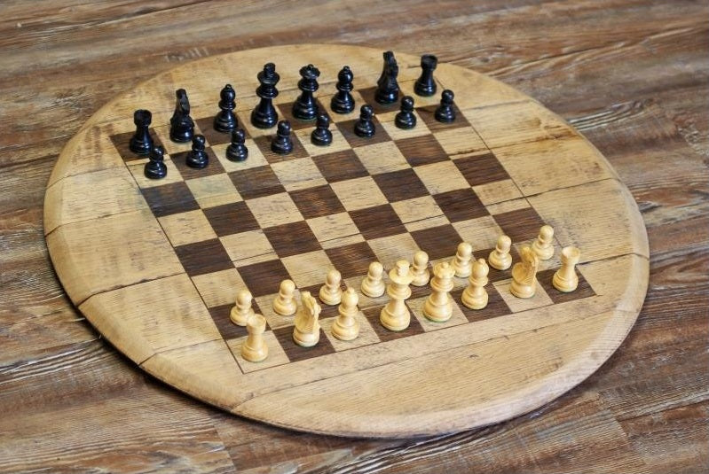 Wooden chessboard with black and white chess pieces on a wooden surface