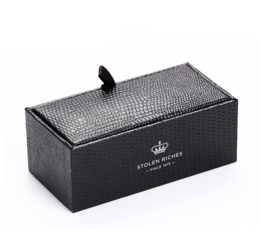 A box containing a tie bar, the box has "Stolen Riches since 1915" written on it.