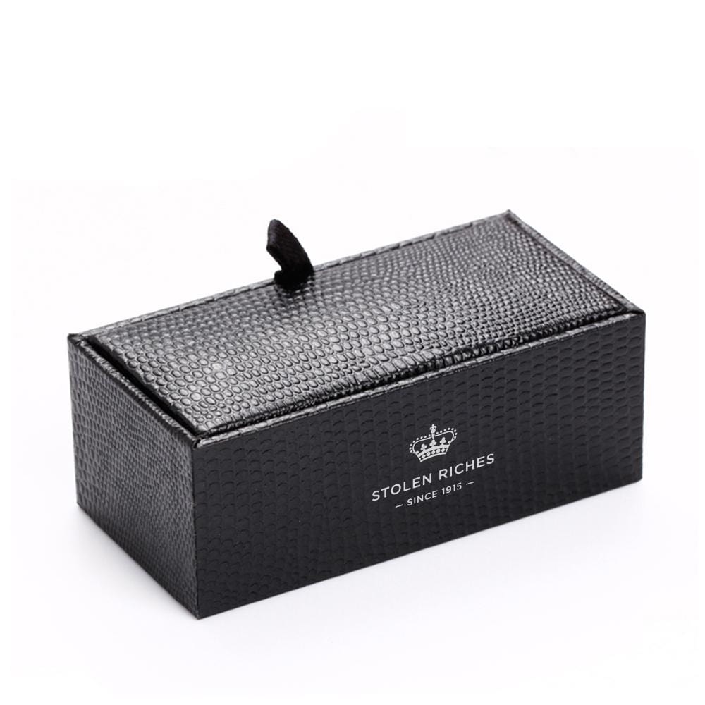 A box containing a tie bar, the box has "Stolen Riches since 1915" written on it.
