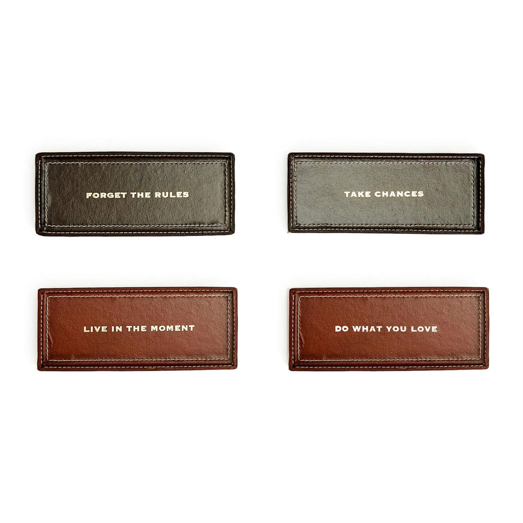 Four leather trinket trays with motivational phrases on a white background