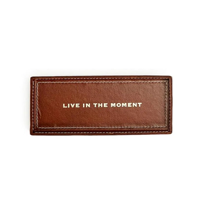 Brown leather tray with 'Live in the Moment' text on a white background