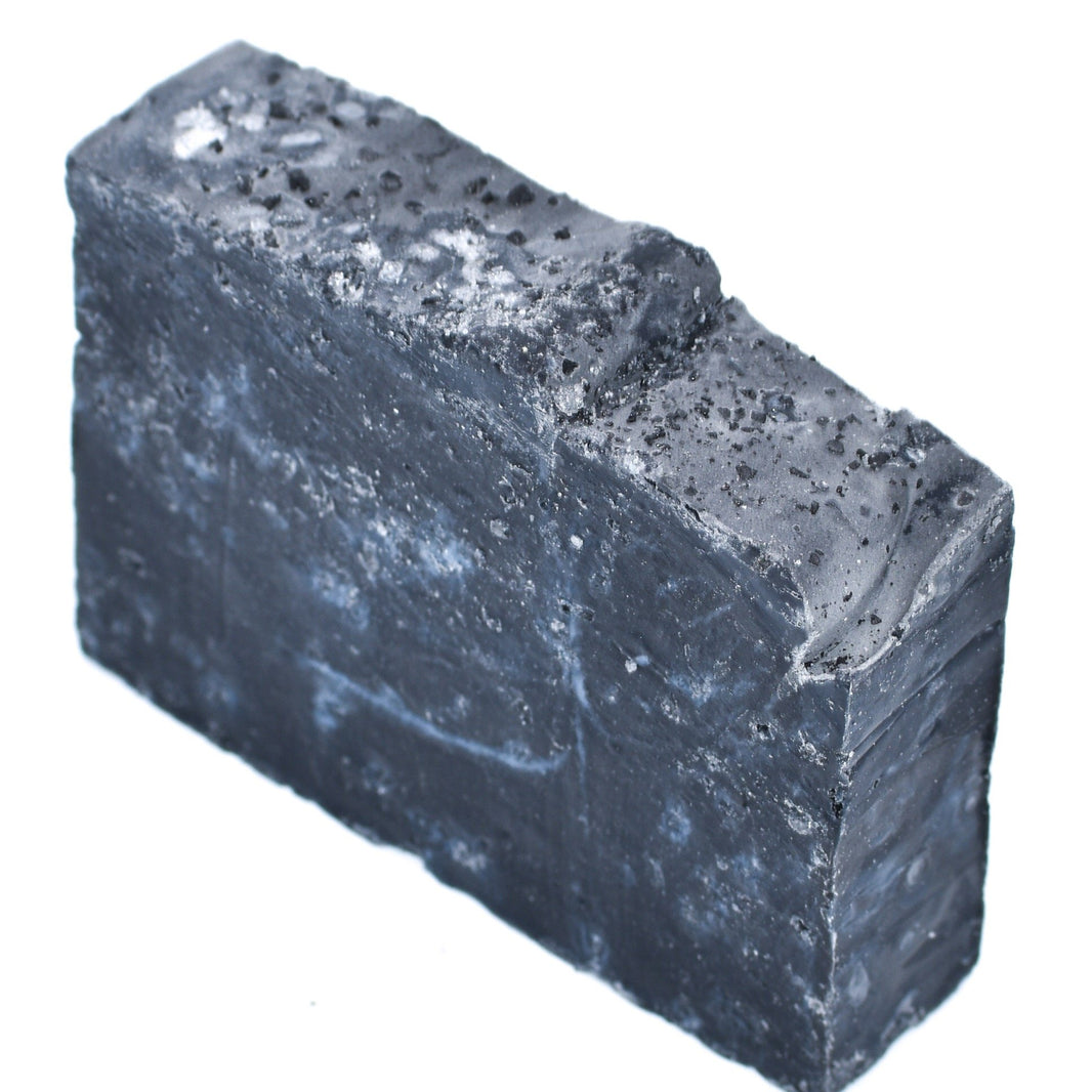 Block of dark soap with a rough texture on a white background