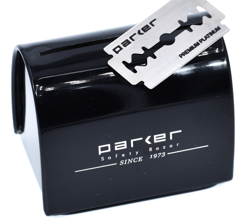 A black metal Parker blade disposal bank with a safety razor blade placed on top of it.